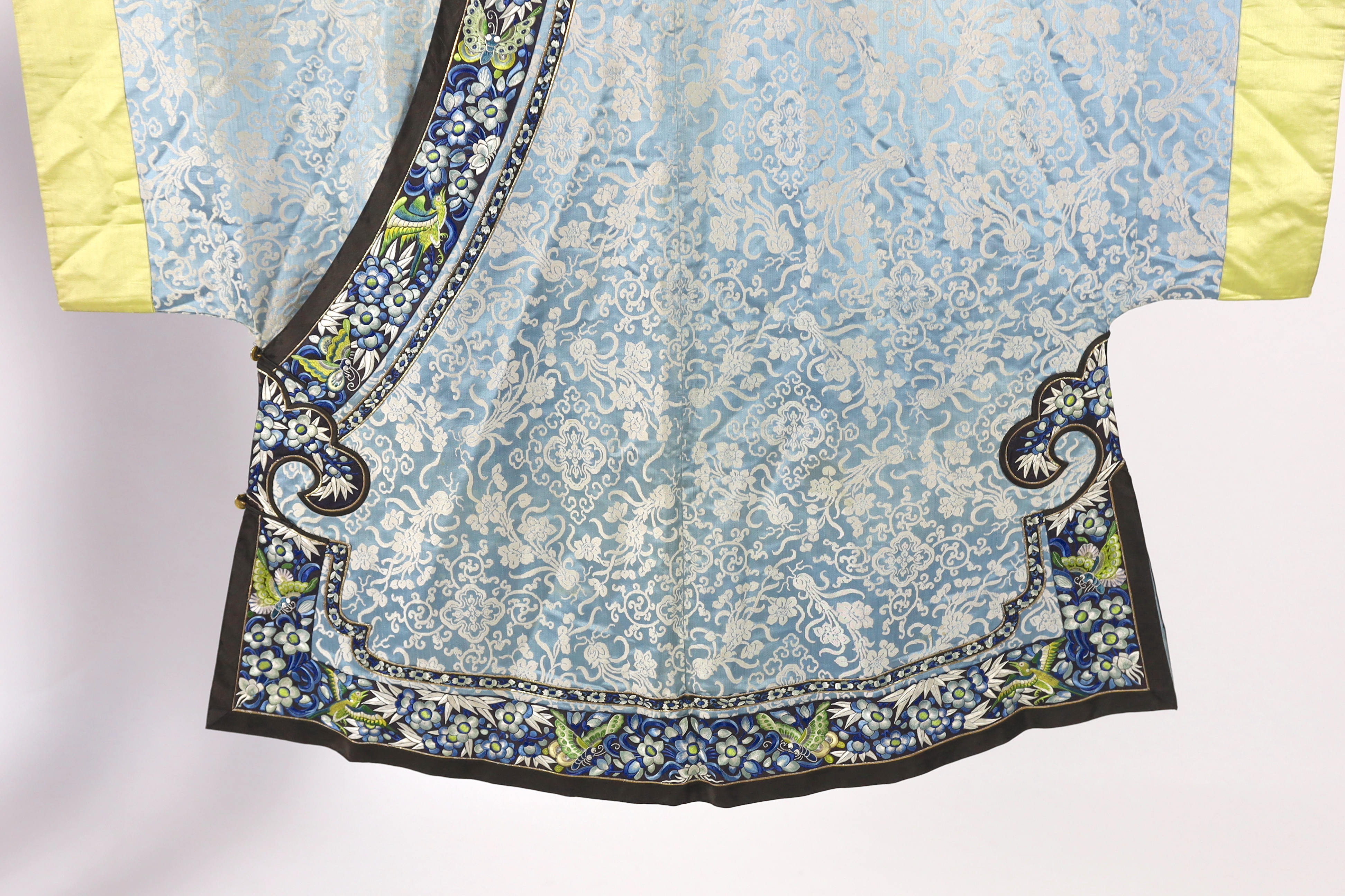 A late 19th / early 20th century silk damask robe, edged with highly ornate embroidered silk braiding, edged with fine gold and black borders, with yellow silk embroidered sleeve bands, the blue silk lining is faded in p